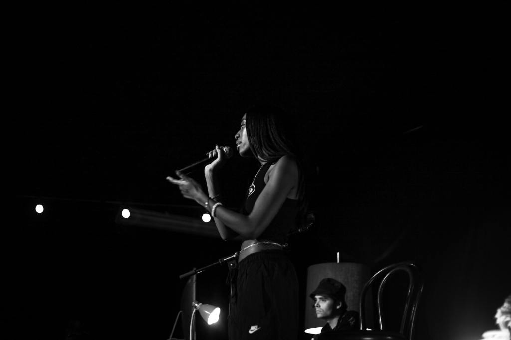 Black and white photo of Jaydon singing into a handheld mic on stage.
